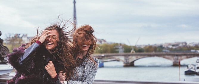Zwei junge Frauen auf einer Brücke in Paris.
