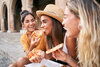 Drei junge Frauen essen auf einem Platz in Italien Pizza.